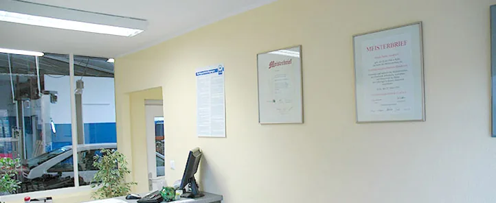 Annahme der Werkstatt mit Blick in die Halle, an der Wand hängen zwei Meisterbriefe